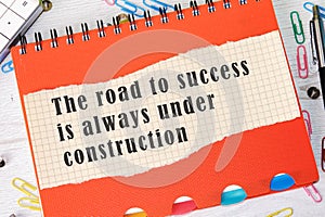 The road to success is always under construction text the phrase is written on a piece of paper in a cage on the background of an