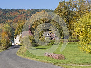 Road to the village chapel in autumn rural landscape with straw