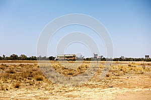 Road train and dry grass  in a flat dry desert landscape near Boulia in Outback Queensland, Australi