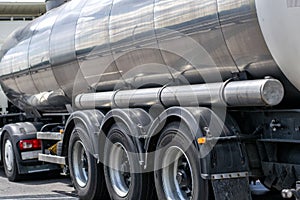 Road train with a tanker driving on the road, left rear view