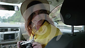 Road trip, girl in straw hat has fun and photographs on retro while traveling while on car on summer weekend, lifestyle