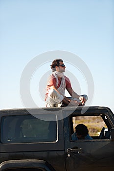 Road trip, man and sitting on car roof for scenery, nature and fresh air on adventure or vacation in South Africa
