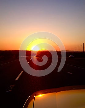 Road trip people in car driving into sunset on freeway