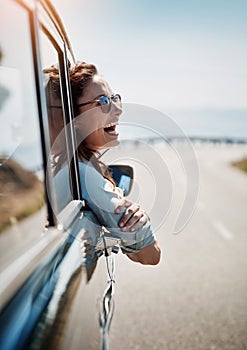 Road trips put me in a happy mood. an attractive woman hanging out of a car window while enjoying a road trip.