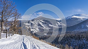 The road, trodden in the snow, runs along the hillside.