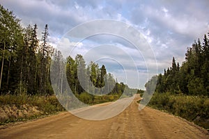 Road trough nature with green forest and blue sky during summer. Gravel dirt road. Fire protection.