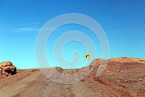 Road turn with yellow road sign in the Atacama desert, Chile