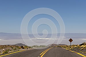 Road turn with yellow road sign in the Atacama desert, Chile