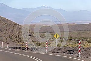 Road turn with yellow road sign in the Atacama desert, Chile