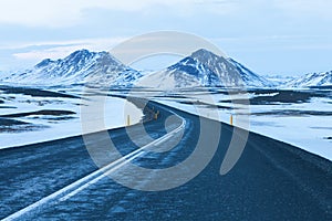 The road at twilight through the snow capped mountains