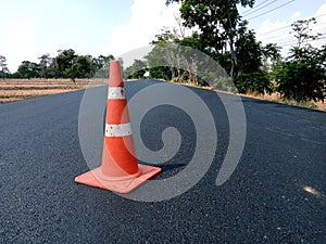 The road is under construction and has a red rubber cone on the road