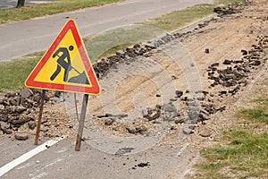 Road is under construction with a warning sign and new asphalt laid