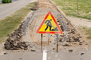 Road is under construction with a warning sign and new asphalt laid