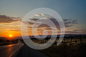 Road vanishing to the horizon under sun rays coming down trough the dramatic stormy clouds. Sunset at the mountain road. Azerbaija