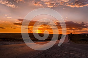 Road vanishing to the horizon under sun rays coming down trough the dramatic stormy clouds. Sunset at the mountain road. Azerbaija