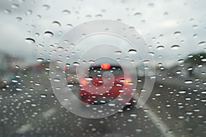 Road view through car window with rain drops driving in rain.