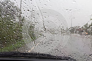 Road view through car windshield with rain drops