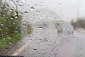 Road view through car windshield with rain drops