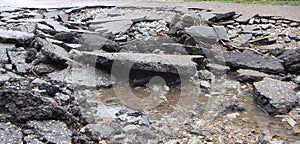 Road of the water erosion, broken asphalt background. Danger hole, stone gray backdrop. Close-up photo