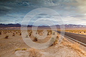 landscape with a road crossing the desert of death valley in California with the mountains in the background