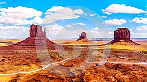 Road winding around Red Sandstone Formations of West Mitten, East Mitten Buttes and Merrick Butte in Monument Valley