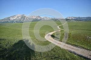 The road winding and disappearing at the distance, the Durmitor mountain at the background