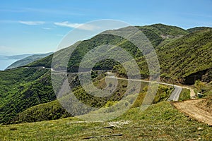 Road winding in green landscape under blue sky