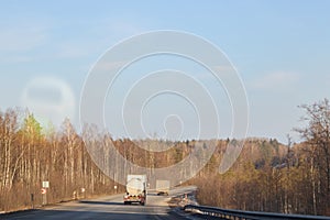 Road and winter forest with yellow trees and cars