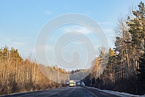 Road and winter forest with yellow trees and cars