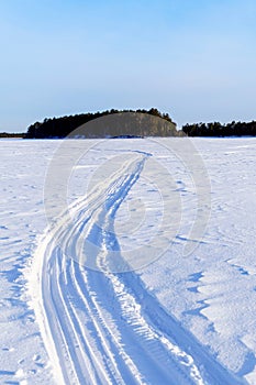 The road on the winter lake sunny winter day. space for copying text. Vertical photo