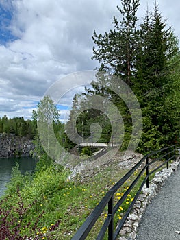 Road and wooden observation deck on the edge of Marble Canyon in Ruskeala Mountain Park on a summer day