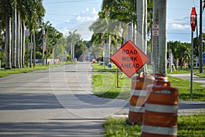 Road work ahead sign and barrier cones on street site as warning to cars about construction and utility works