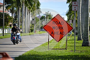 Road work ahead sign on street site as warning to cars about construction and utility works