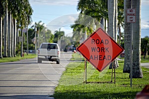 Road work ahead sign on street site as warning to cars about construction and utility works