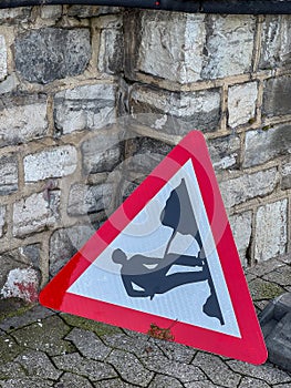 Road Work Warning Sign Leaning Against Stone Wall