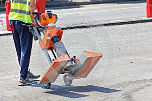 A road worker carries a powerful petrol drill to collect asphalt concrete samples