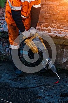 Road worker drilling asphalt on pavement with jackhammer