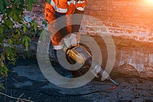 Road worker drilling asphalt on pavement with jackhammer