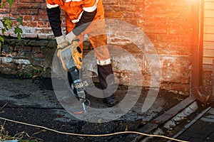 Road worker drilling asphalt on pavement with jackhammer