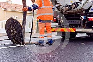 road worker and his truck cleaning the sewers on a road