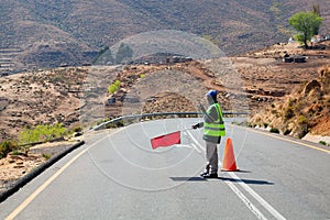 Road worker holds in hand red flag prohibiting traffic, travel restrictions, road repair, customs border transport control