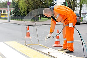 Road worker marking pedestrian crossing line