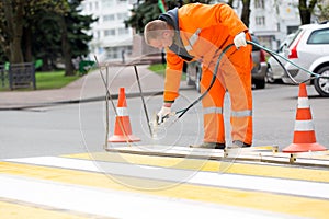 Road worker marking street lines zebra crossing