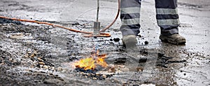 Road worker prepare pothole with gas torch flame for repairing. copy space