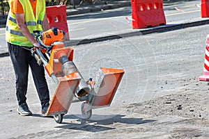 A road worker pulls a petrol drill to cut asphalt concrete samples