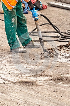 A road worker smashes old asphalt with a pneumatic jackhammer at a work site
