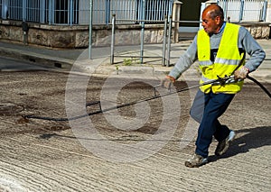 Road worker spraying bitumen emulsion