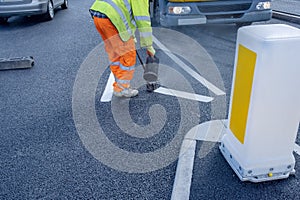 Road workers applying hot melt traffic resistant paint for white, yellow and red road marking lines on new build asphalt road