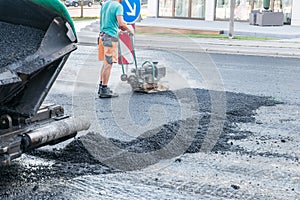 Road workers compact the asphalt with a vibrating rammer on the road, Germany