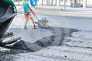 Road workers compact the asphalt with a vibrating rammer on the road, Germany